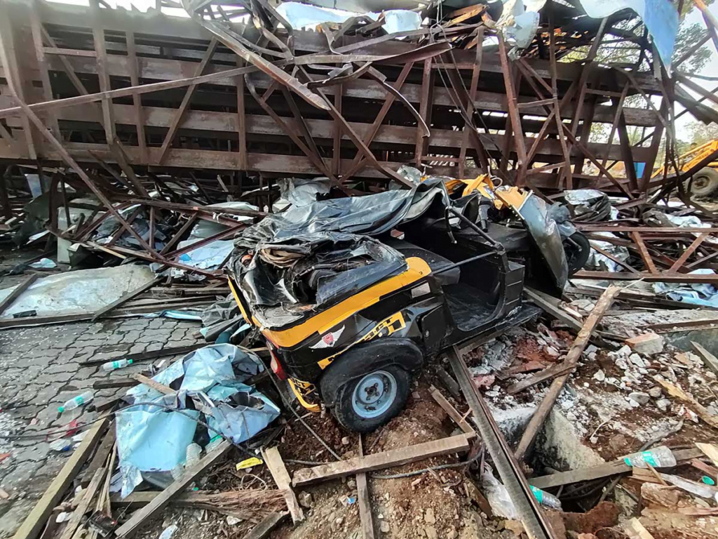 Damaged rickshaw lying amidst debris under a collapsed billboard in Mumbai, a stark aftermath of the 2024 storm, highlighting the extensive damage and chaos caused by the severe weather.