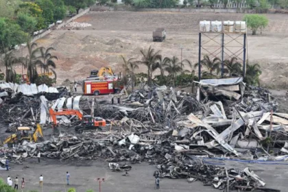 Aerial view of the aftermath of the Rajkot game zone fire, showing the collapsed tin shed structure with rescue workers and fire trucks on site.