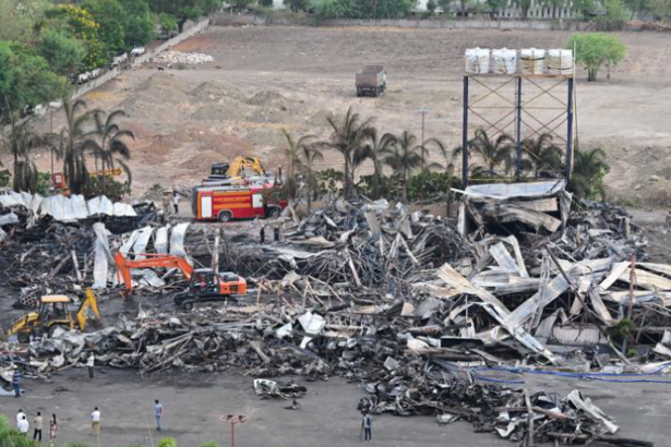 Aerial view of the aftermath of the Rajkot game zone fire, showing the collapsed tin shed structure with rescue workers and fire trucks on site.