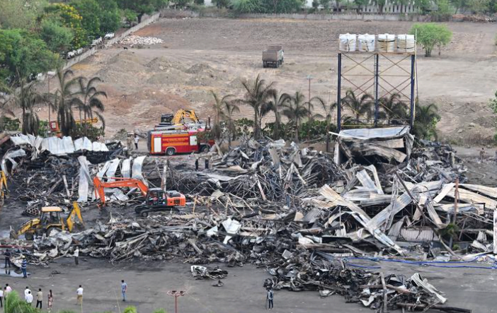 Aerial view of the aftermath of the Rajkot game zone fire, showing the collapsed tin shed structure with rescue workers and fire trucks on site.
