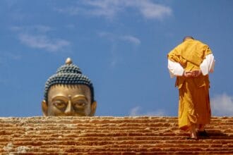 A serene artistic depiction of Gautama Buddha in meditation, surrounded by symbolic elements like the lotus flower, representing purity, and the Bodhi tree, symbolizing enlightenment. The peaceful ambiance highlights Buddhism as one of the world's oldest religions